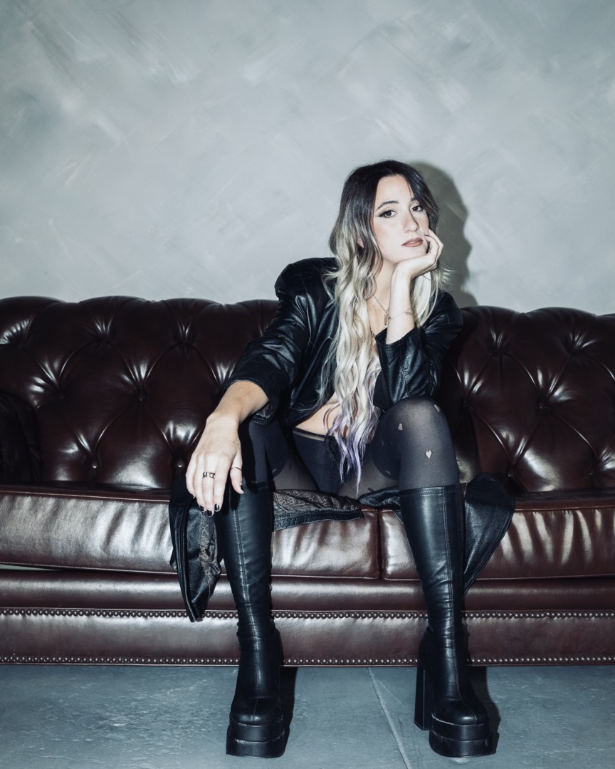 sarah de warren posing on a leather couch