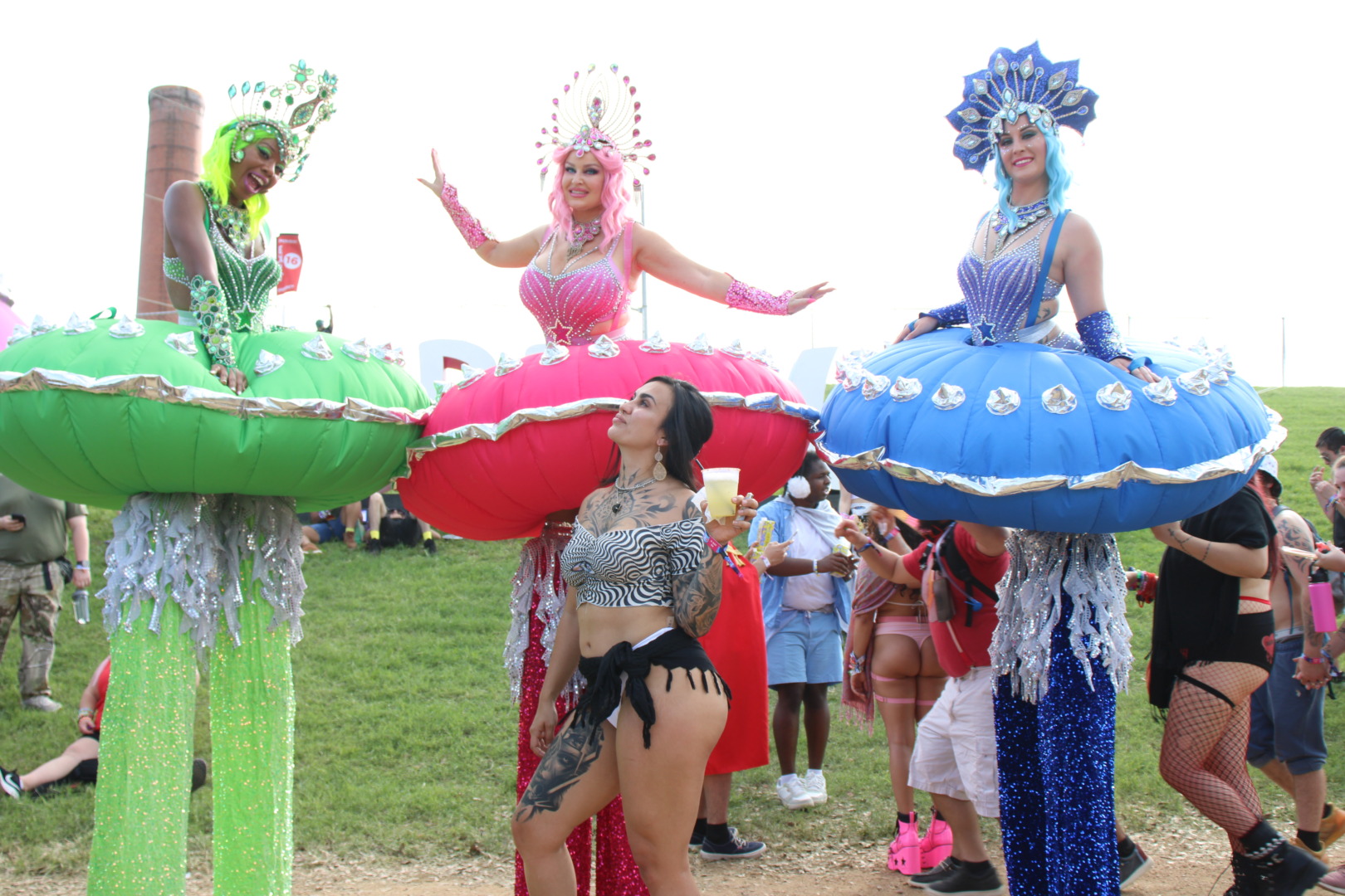 three stilted space ship looking ladies, with a gorgeous brown woman posing in front of them 