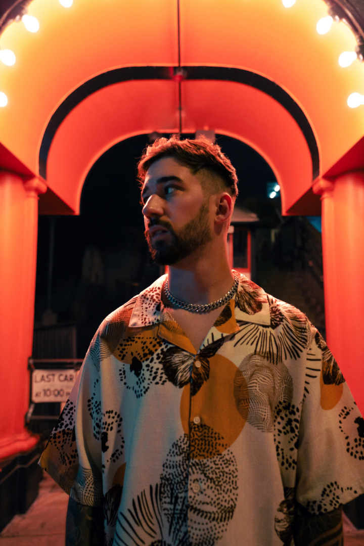 WELKER posing upon a red background in some catherdal like hallway