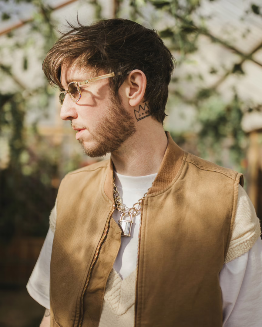 Of The Trees posing with gold rimmed glasses and a forest back ground behind him