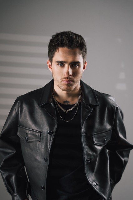 Trym posing in a leather jacket upon a grey back ground with a serious look on his face