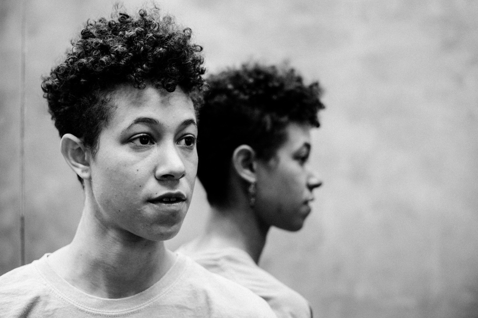 OLAN posing in a black and white phot next to a mirror