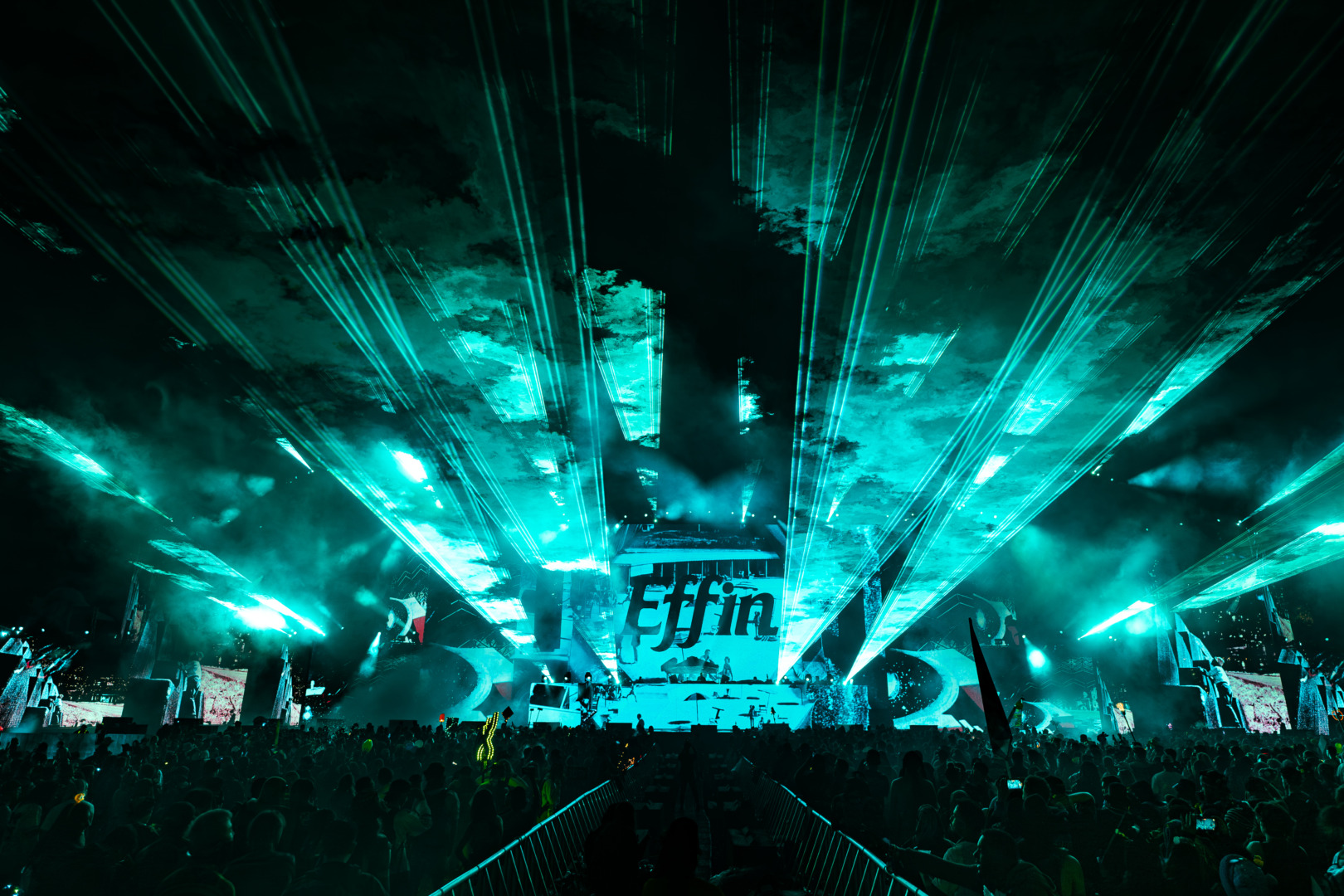 EFFIN stage performance, with a greensih hue with lazers ringing loudly through it