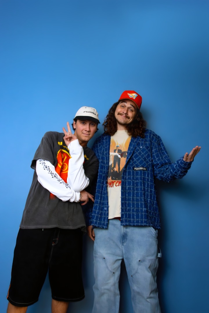 NIIKO X SWAE Rasiing thier hands upon a blue background