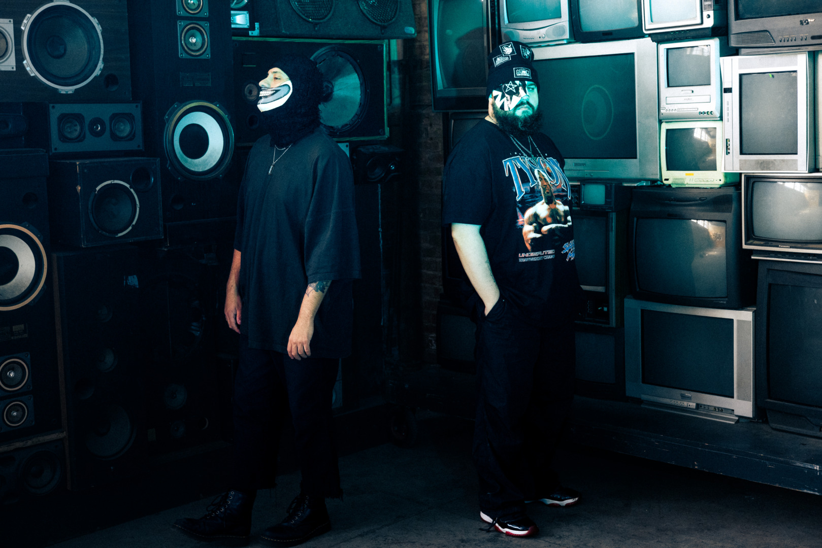 Trickster standing in front of some Tvs with masked on