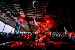 Majed djing with hand in the air underneath a disco ball