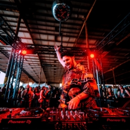 Majed djing with hand in the air underneath a disco ball