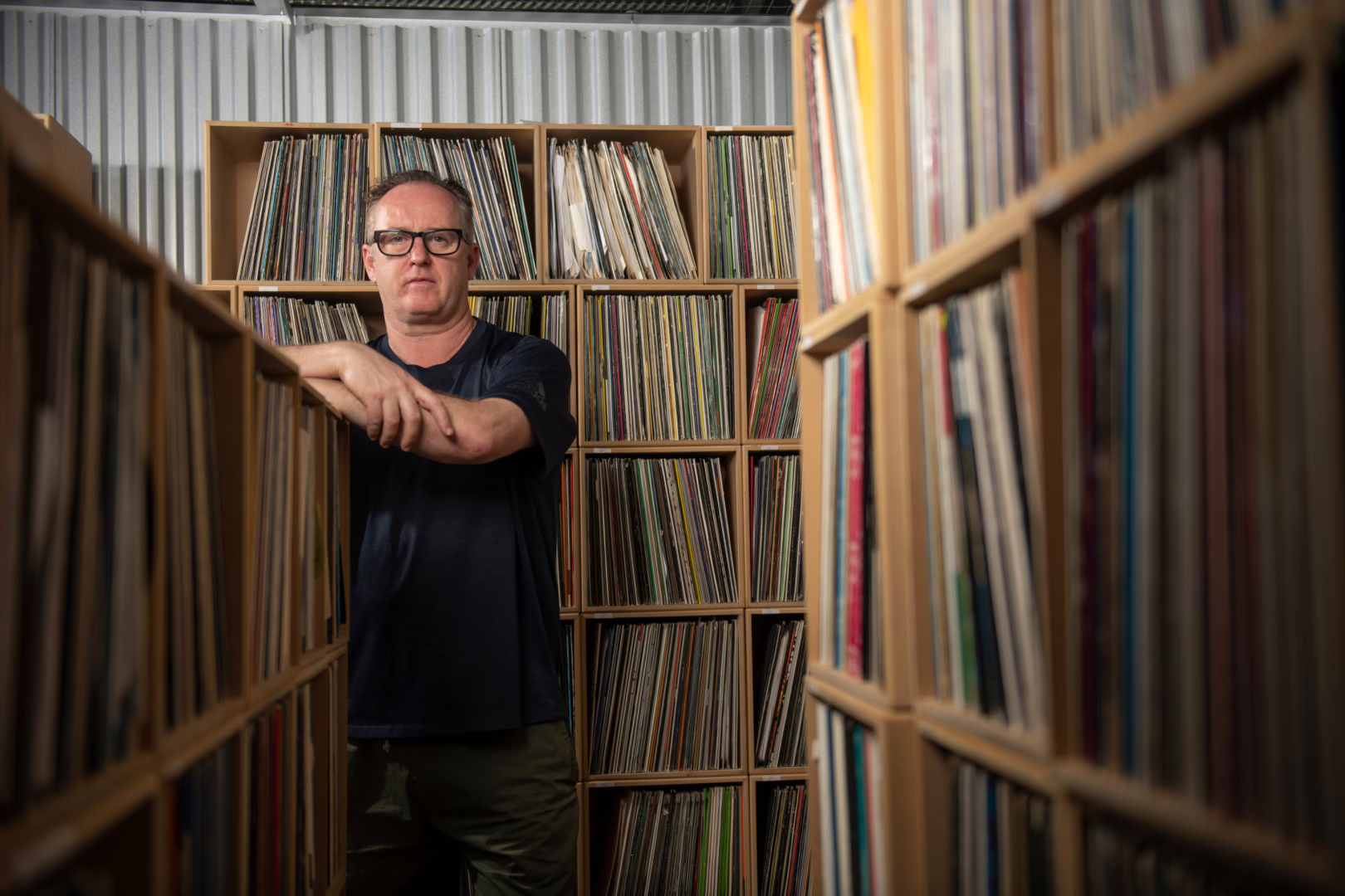 Sasha leaning a huge shelf of reocrds