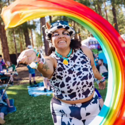 A woman in a cow suit waving a rainbow flag