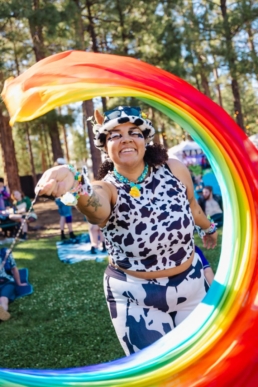 A woman in a cow suit waving a rainbow flag